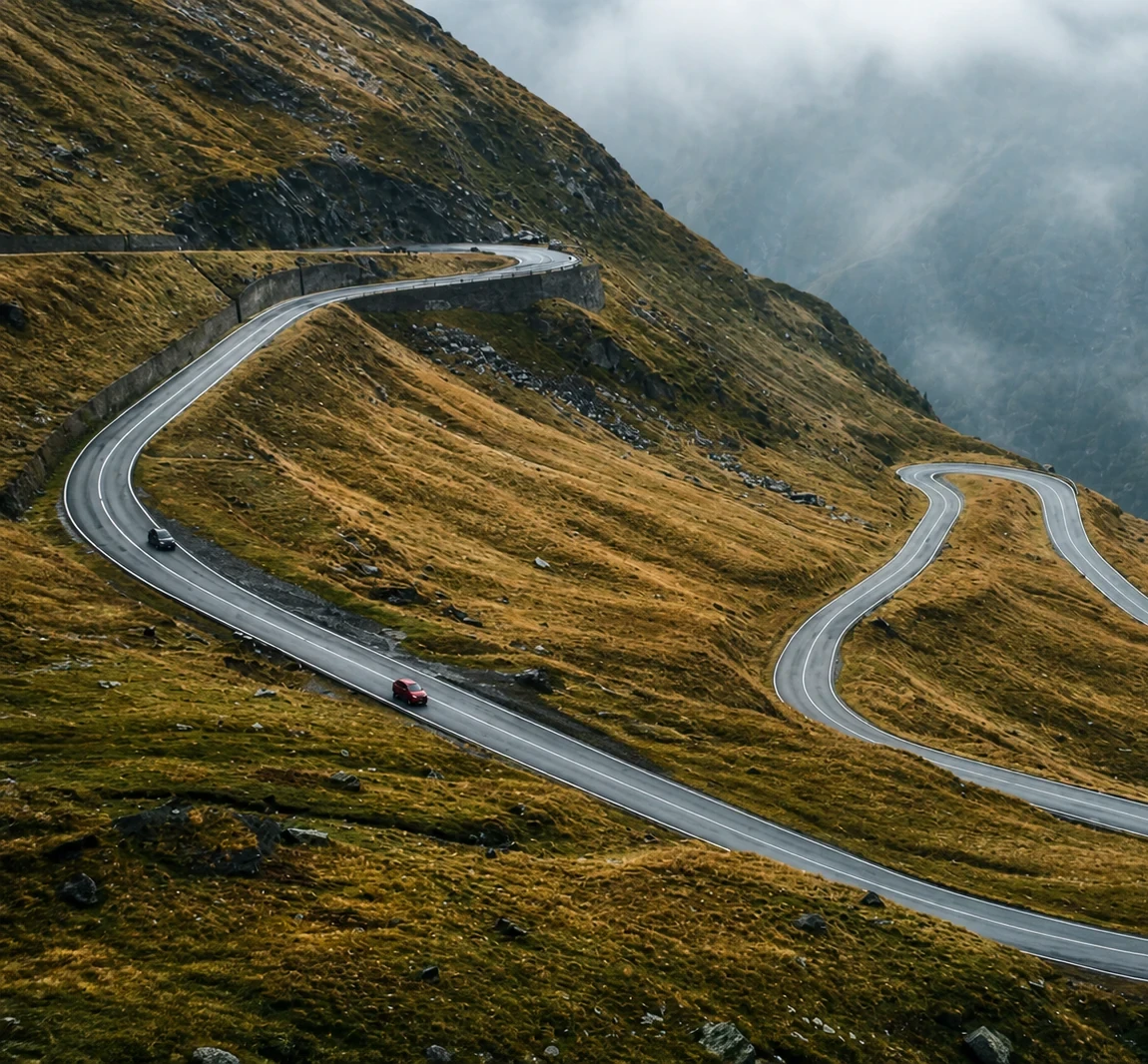 Two connected fleet vehicles travelling along a winding mountain road